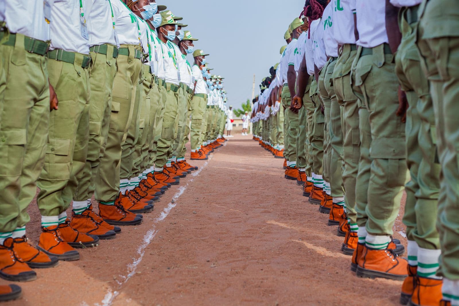 Corps members and security personnel on parade. Many graduates travel long distances to their postings by road, through corridors where armed groups operate.